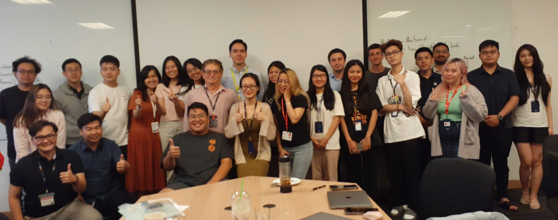 Photo of a group of postgraduate students and a guest lecturer smiling in front of the class