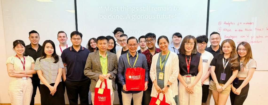 Photo of a lecturer and a group of postgraduate students smiling in front of the class at RMIT Vietnam