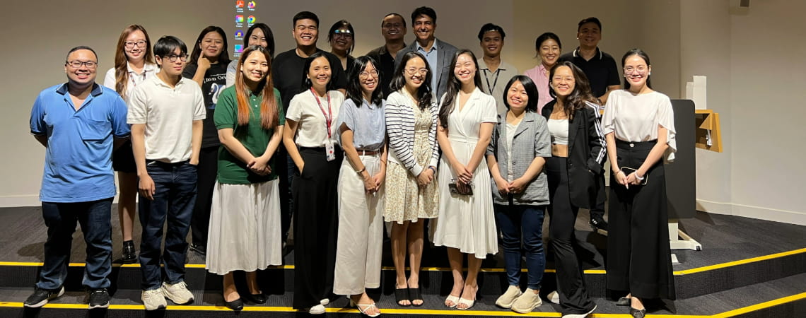 Photo of a group of postgraduate students and a guest lecturer smiling in front of the auditorium at RMIT Vietnam