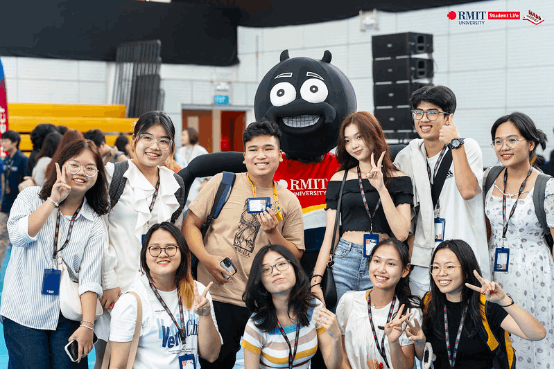 nine students stand behind a photo frame said hello rmit