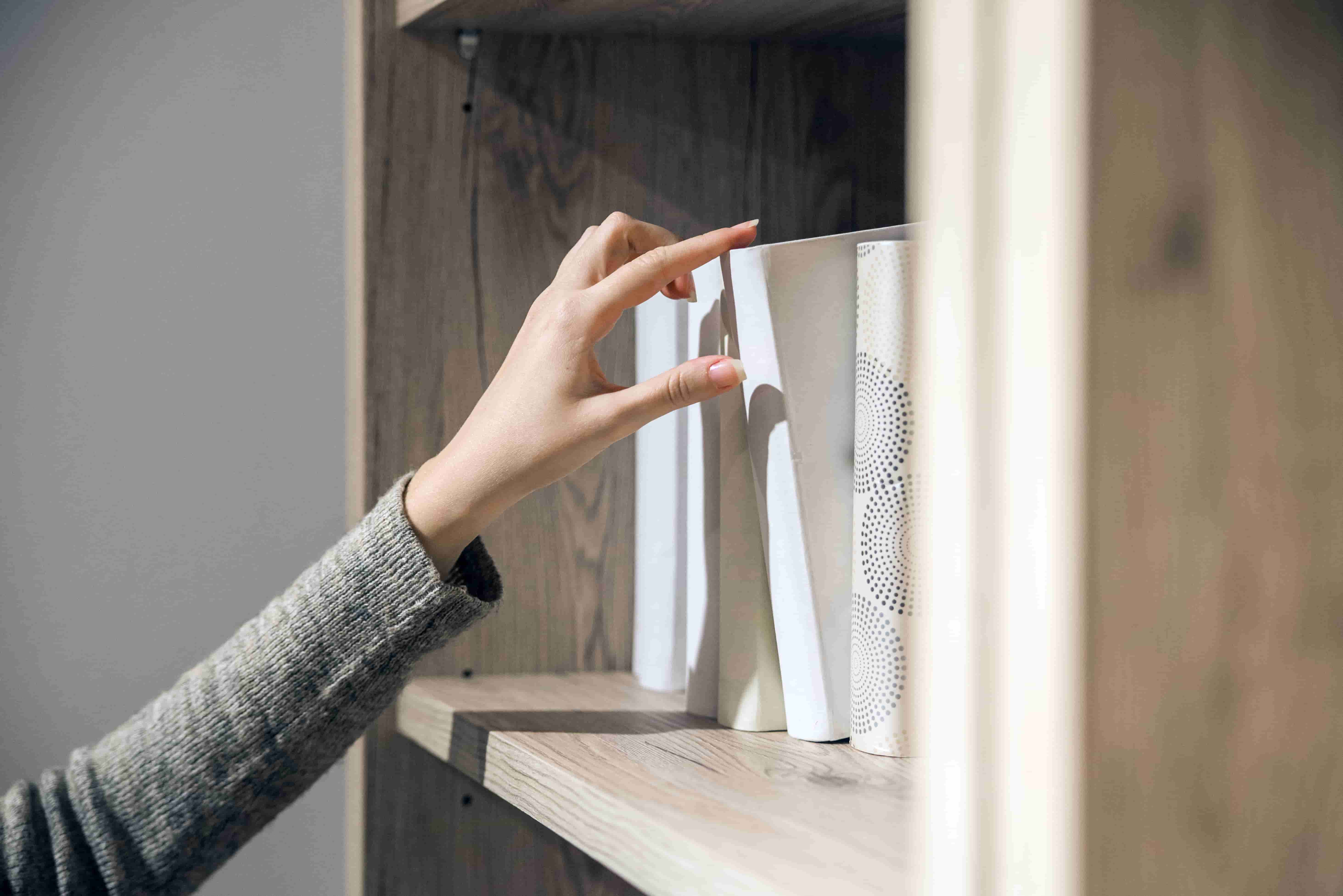 a woman selects book from a bookshelf