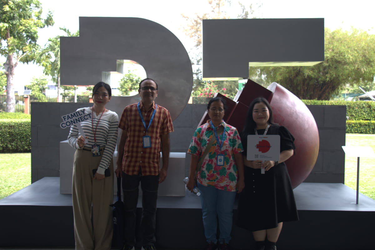 Photo of 2 RMIT staff from Family Connect with two parents standing in front of the RMIT 25th anniversary sculpture at RMIT SGS campus