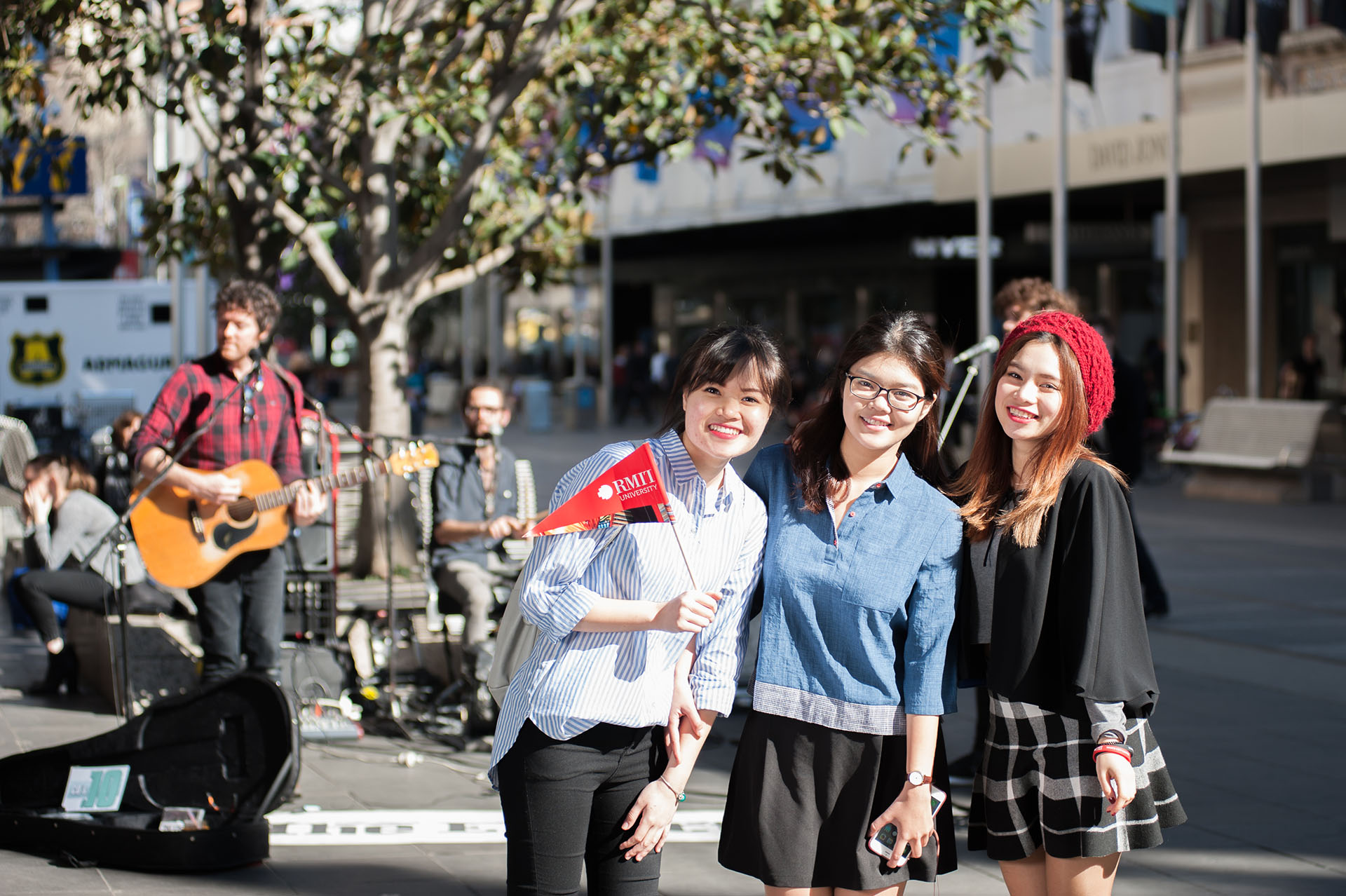 3 Vietnamese exchange students in Melbourne at a market, smiling for the camera