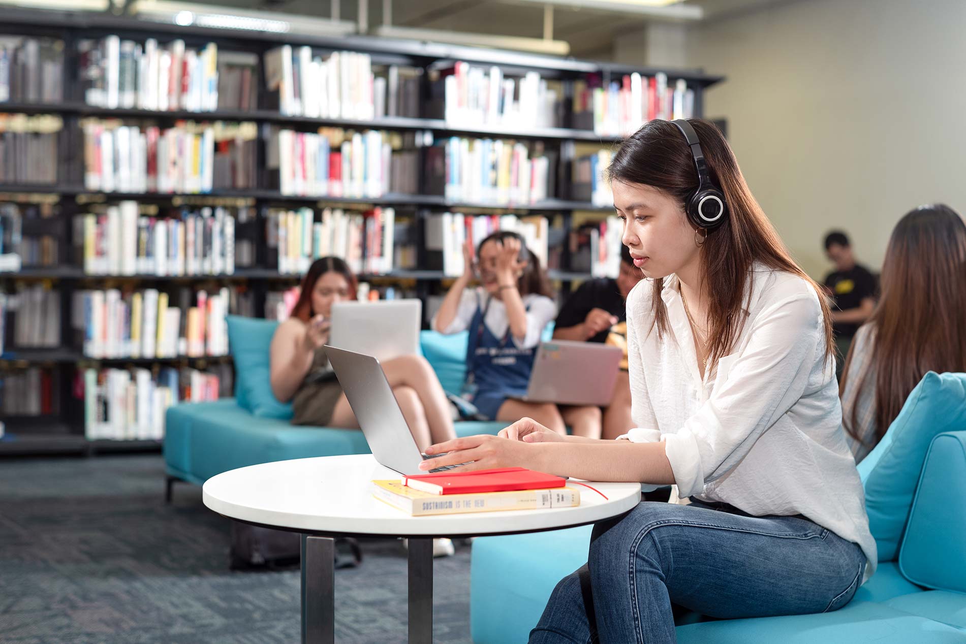 a female student in white shirt and jean studied in the library