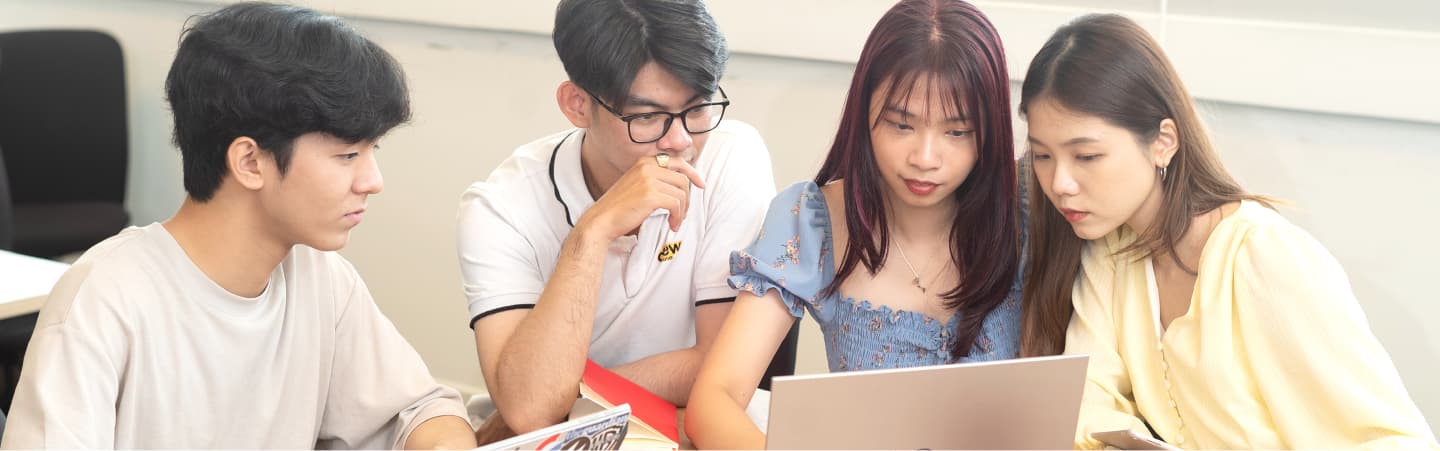 group of students discuss work on laptop