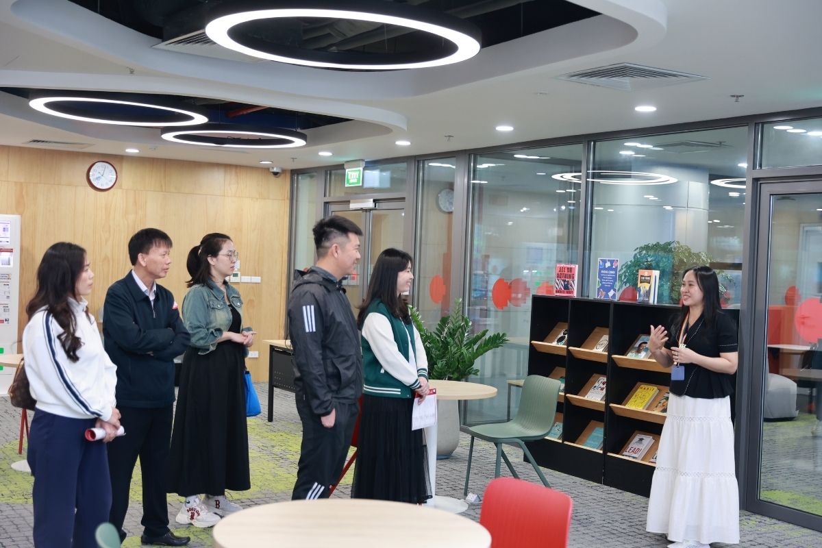 The photo showing a lady give a speech to a group of people inside a library