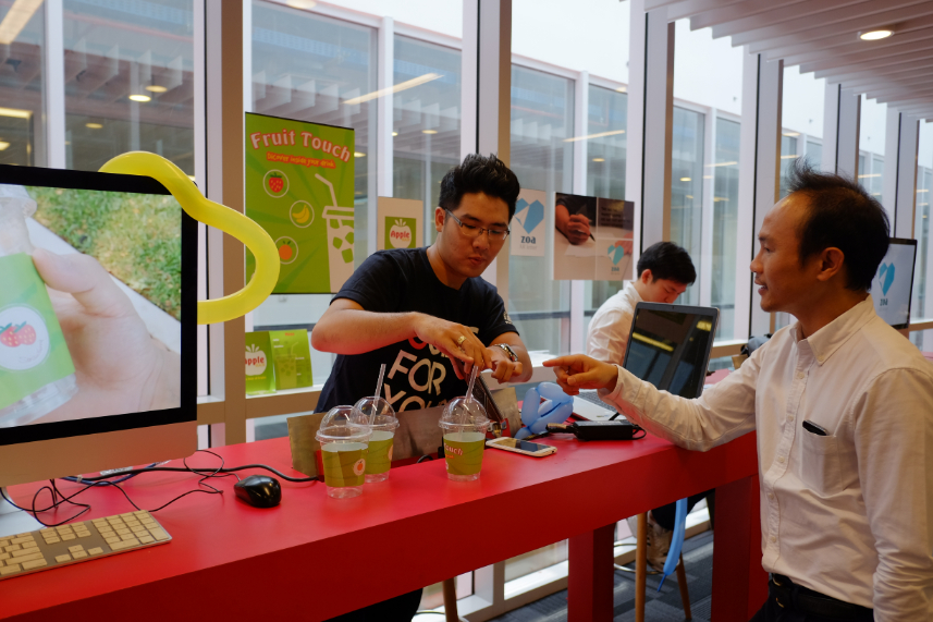 A student explains to Senior Educator Ondris Pui (right) how augmented reality can be used to market fruit juice.