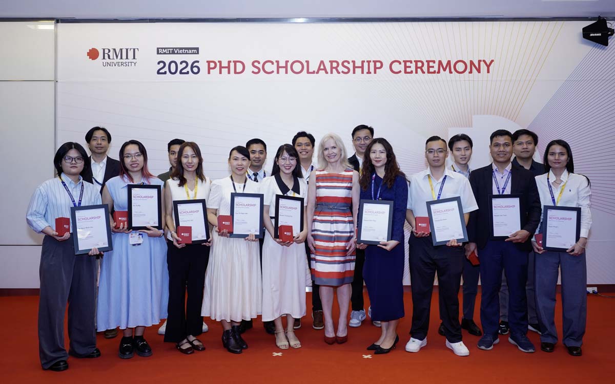 PhD scholarship recipients pose together on stage during the RMIT Vietnam 2026 PhD Scholarship Ceremony, holding certificates in front of the event backdrop.