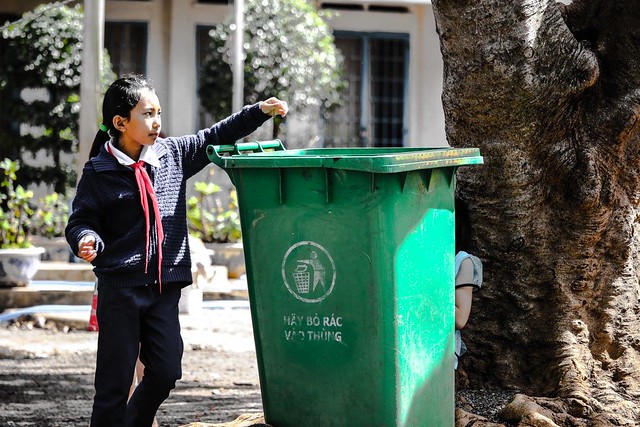 Một em học sinh thể hiện cách bỏ rác vào thùng rác.