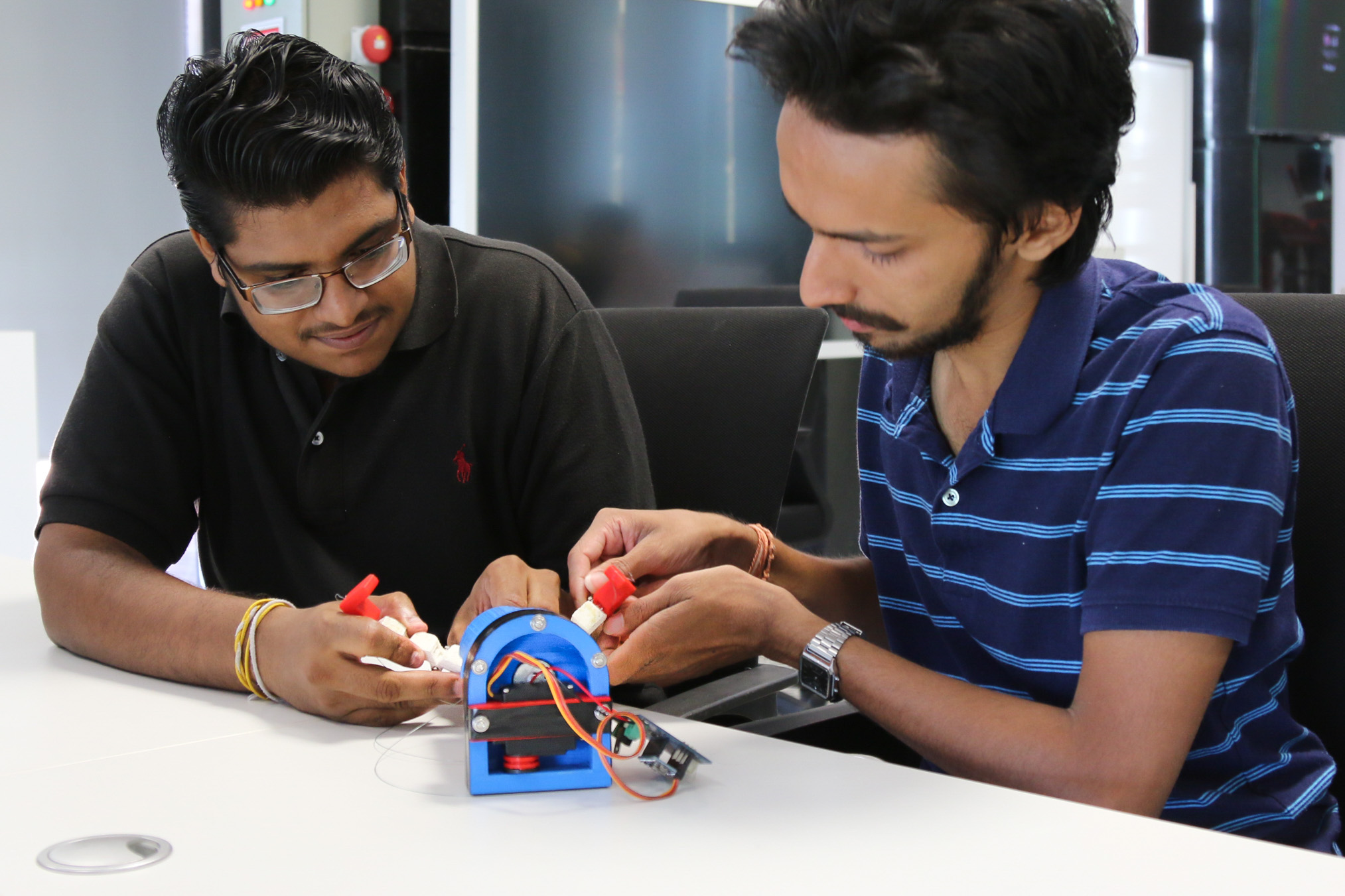 Two Engineering students implementing a part of the prothesis arm project that could help amputees carry out specific tasks.