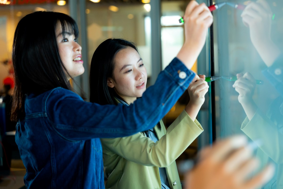 Two female students writing on a board