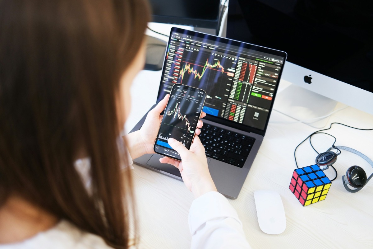 Bitcoin trader looking at bitcoin price charts on smartphone and laptop