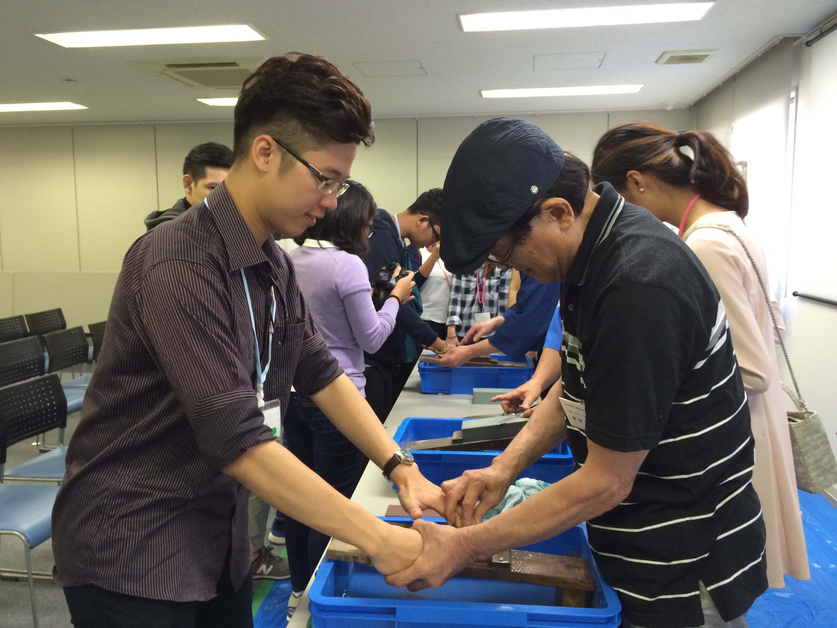 A Sakai craft worker shows Bao how to sharpen a knife professionally.