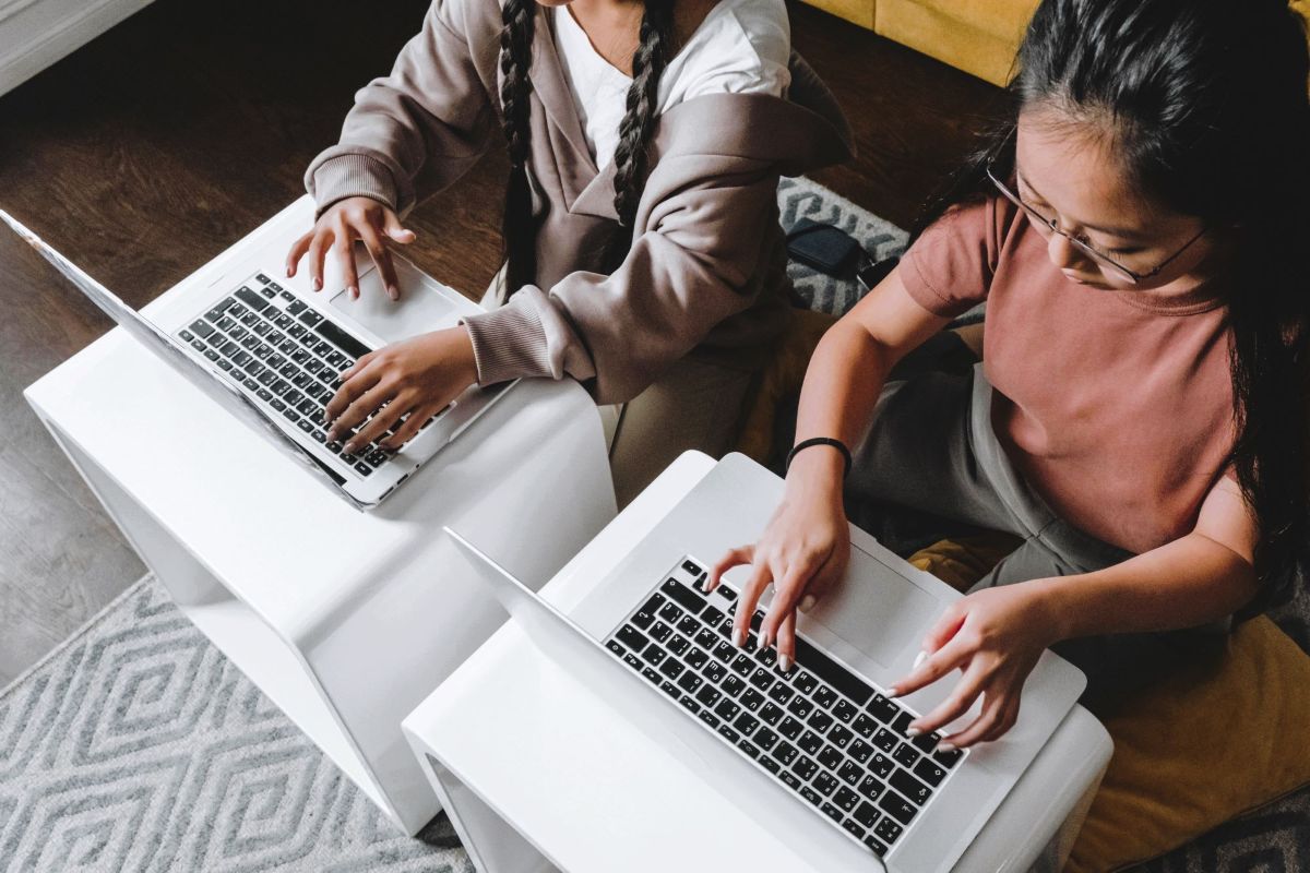 Two children typing on laptops