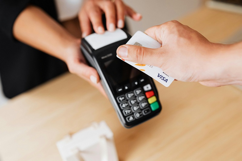A customer hovers a bank card on top of a POS machine