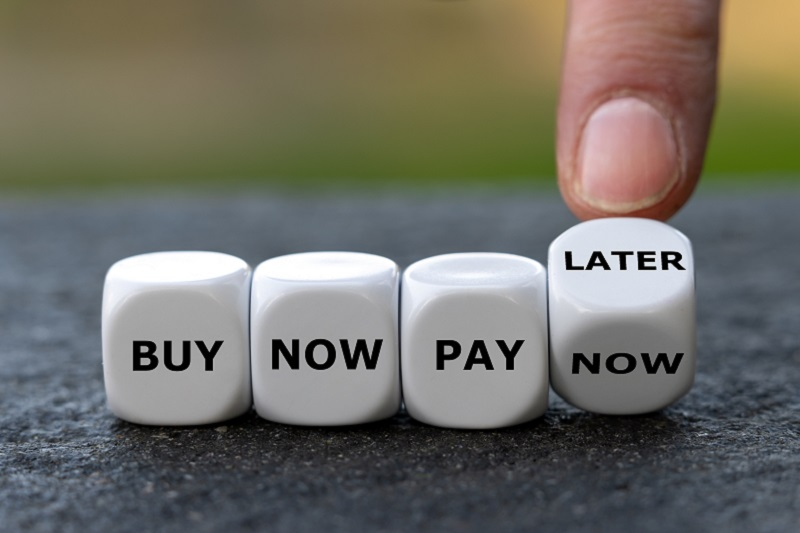 Four white dices showing the words buy, now, pay, later