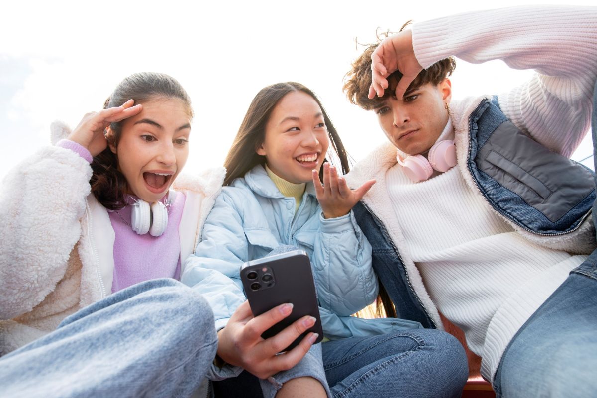 Three young people looking at a phone