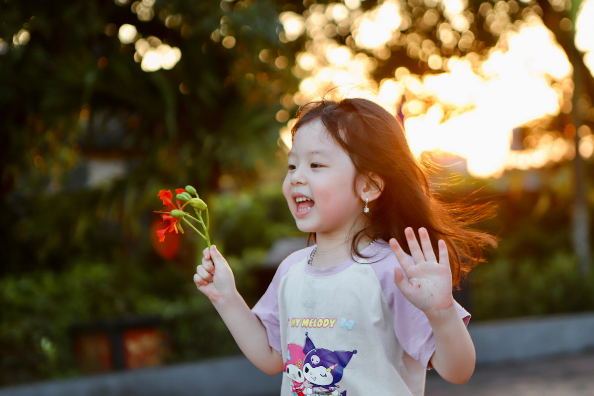happy-little-girl-holding-red-flowers-running-outdoors-at-sunset-golden-hour.jpg