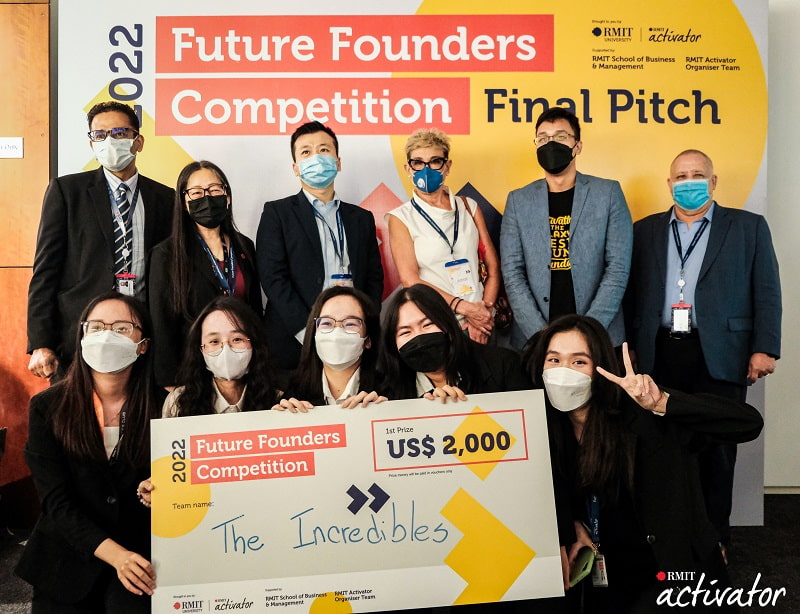 The winning team of the 2022 Future Founders Competition, The Incredibles, standing together with the judges and leaders of the RMIT School of Business & Management, wearing face masks and holding a novelty cheque..