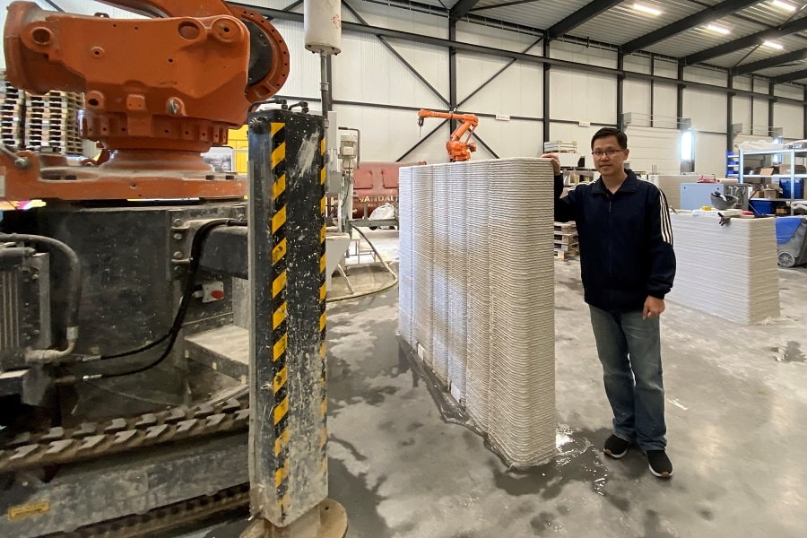 RMIT STEM College Senior Lecturer Dr Jonathan Tran next to a 3D-printed concrete wall.