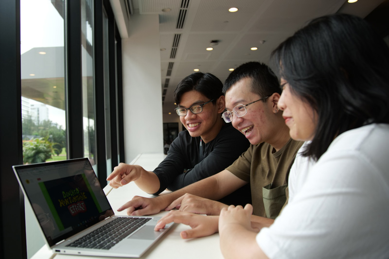 Three members of the team smiling at a laptop