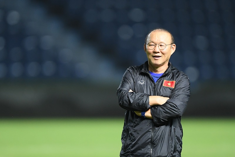 Coach Park Hang-seo smiling on a football field.