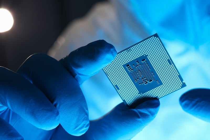 Gloved hands holding a semiconductor chip