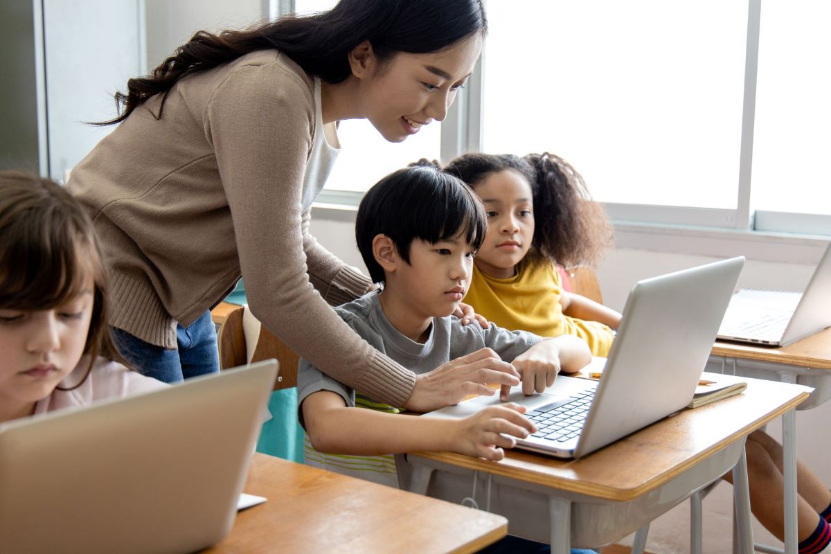 Teacher shows students a lesson on a laptop