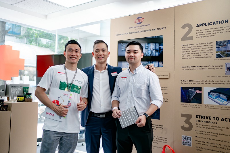 Three men pose in front of a showcase booth