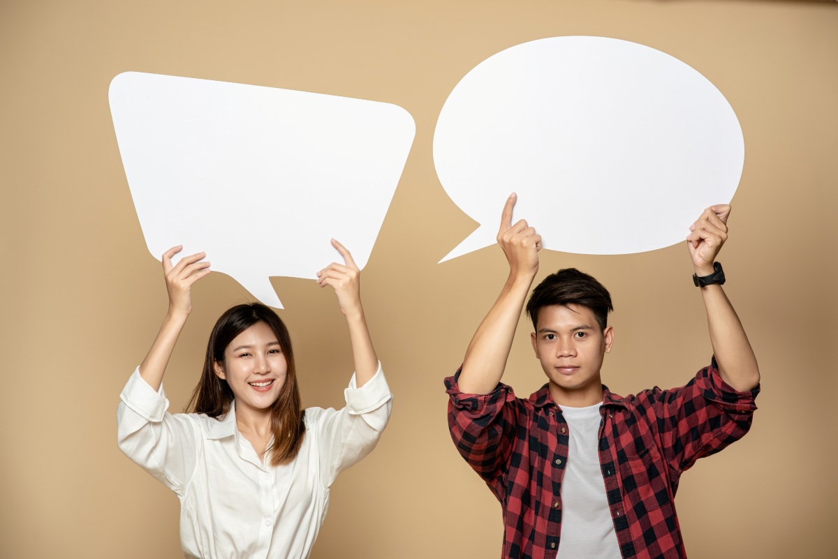 Two people holding up speech bubble signages