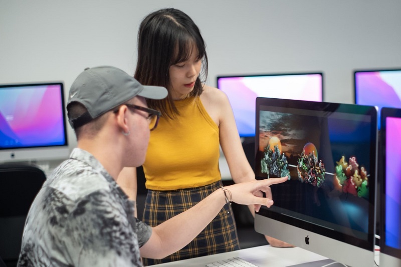 Two students looking at a computer screen with graphics