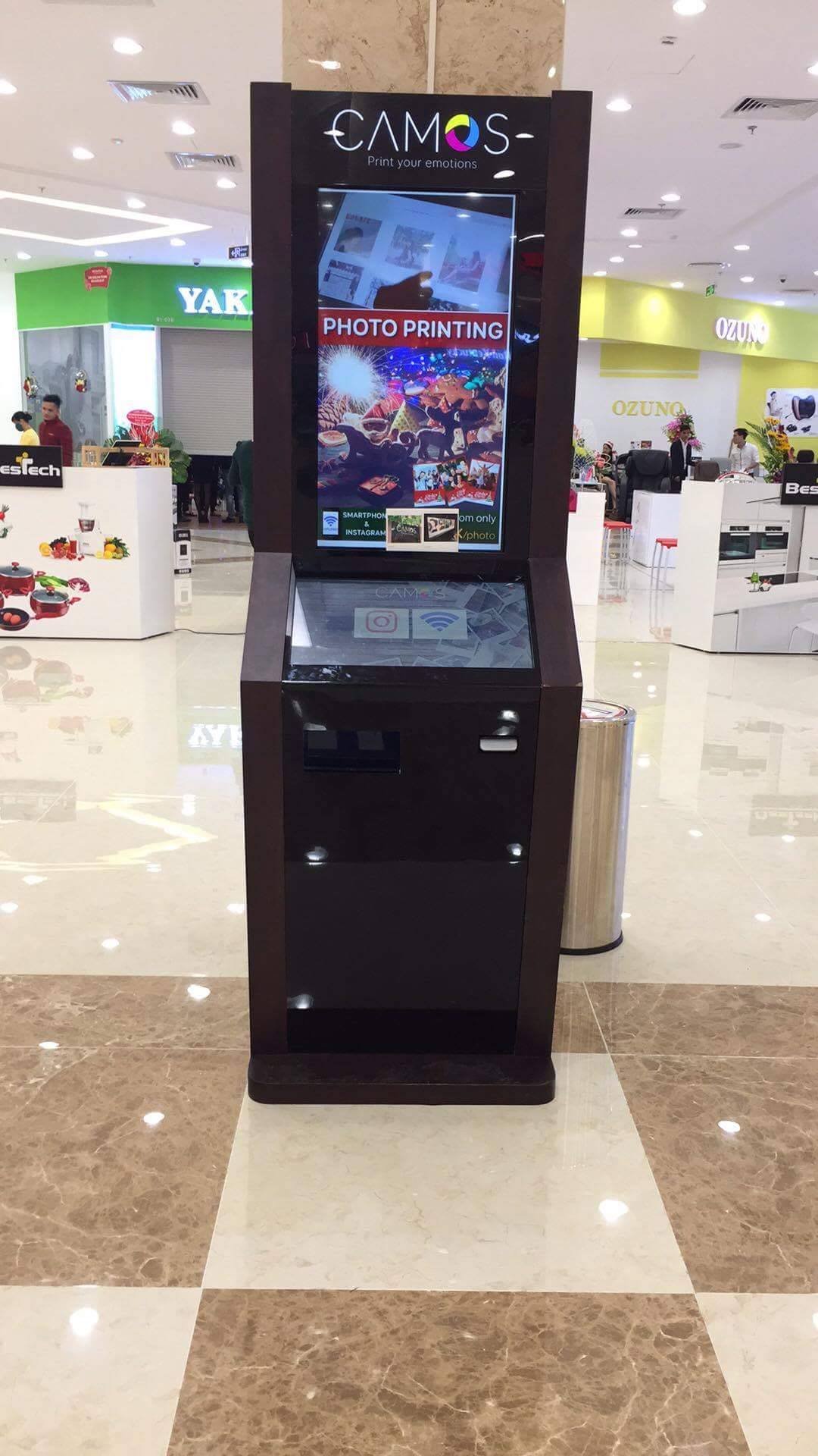 A Camos photo printing kiosk is set up in a mall.