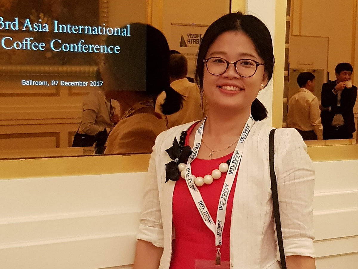 An Asian woman in red top, while blazer and black glasses smiling