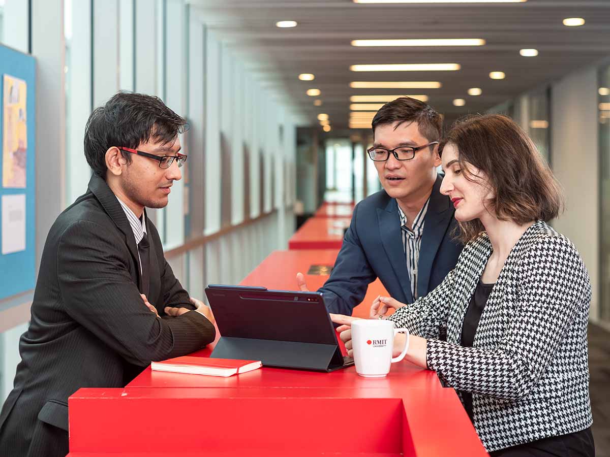 Postgraduate students discussing work on tablet