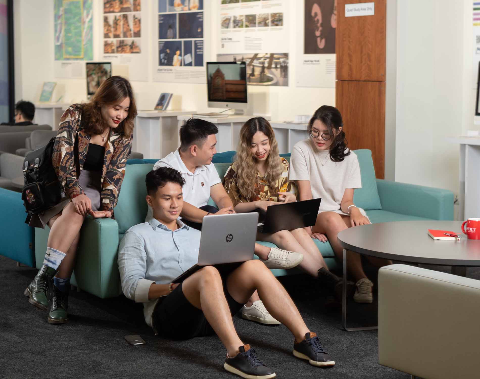 five students discussing work on a sofa