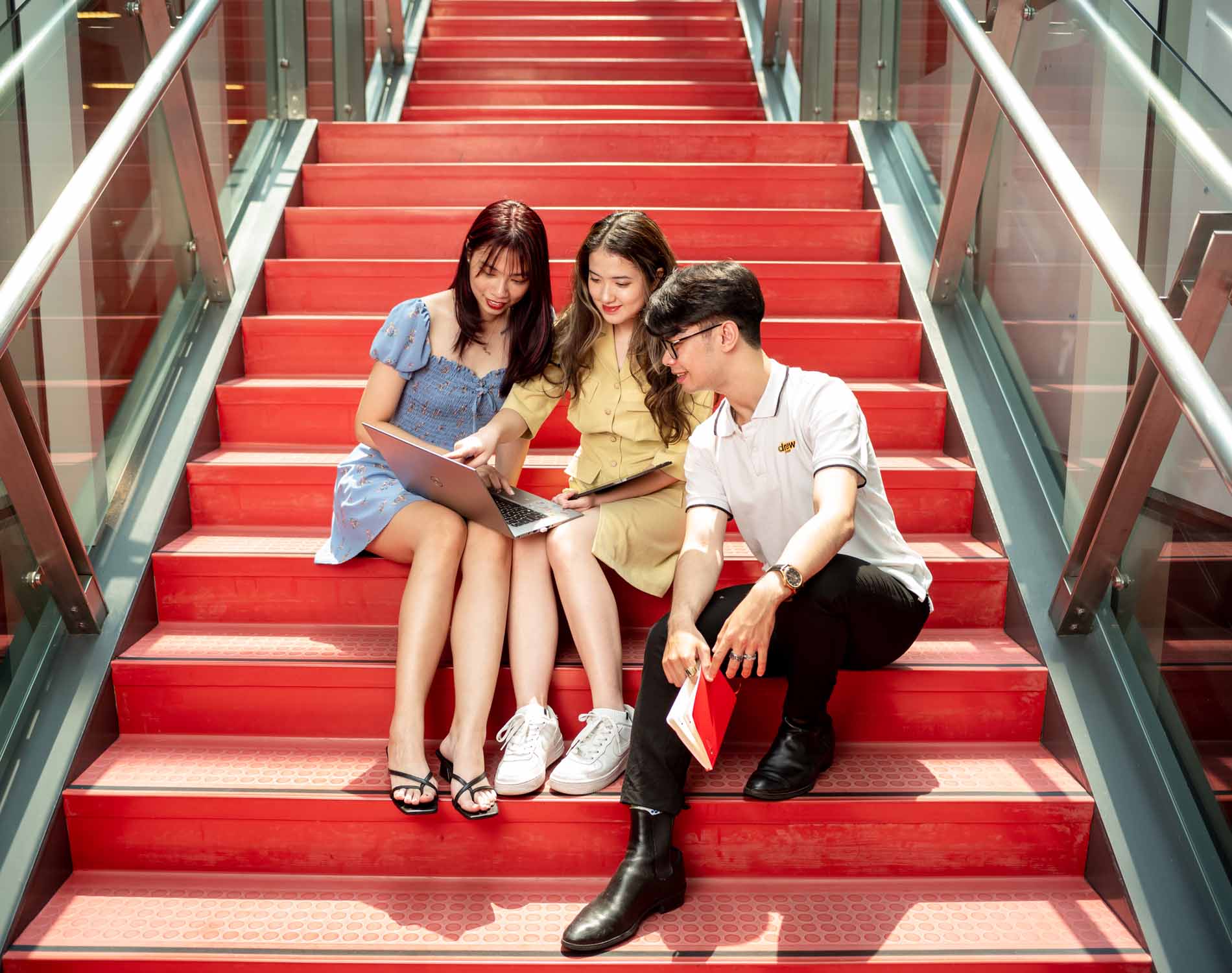 three students discussing work sitting on a staircase