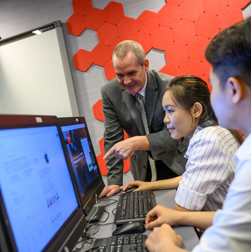 Students with lecturer looking at computer