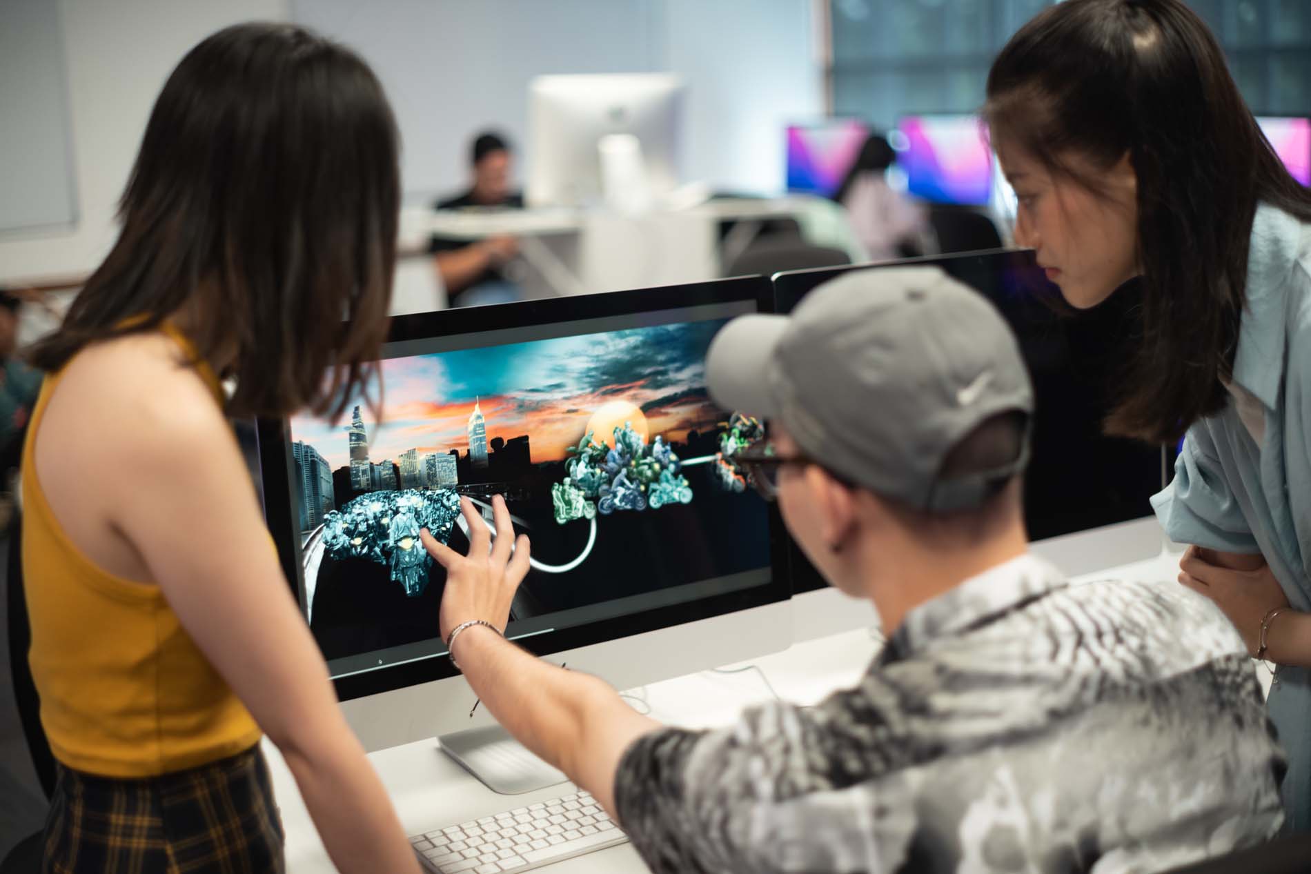 Three students are discussing work on the computer screen