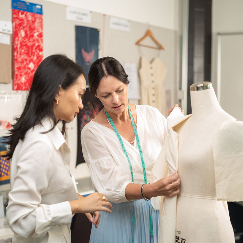 Teacher and student adjusting cloth on a mannequin