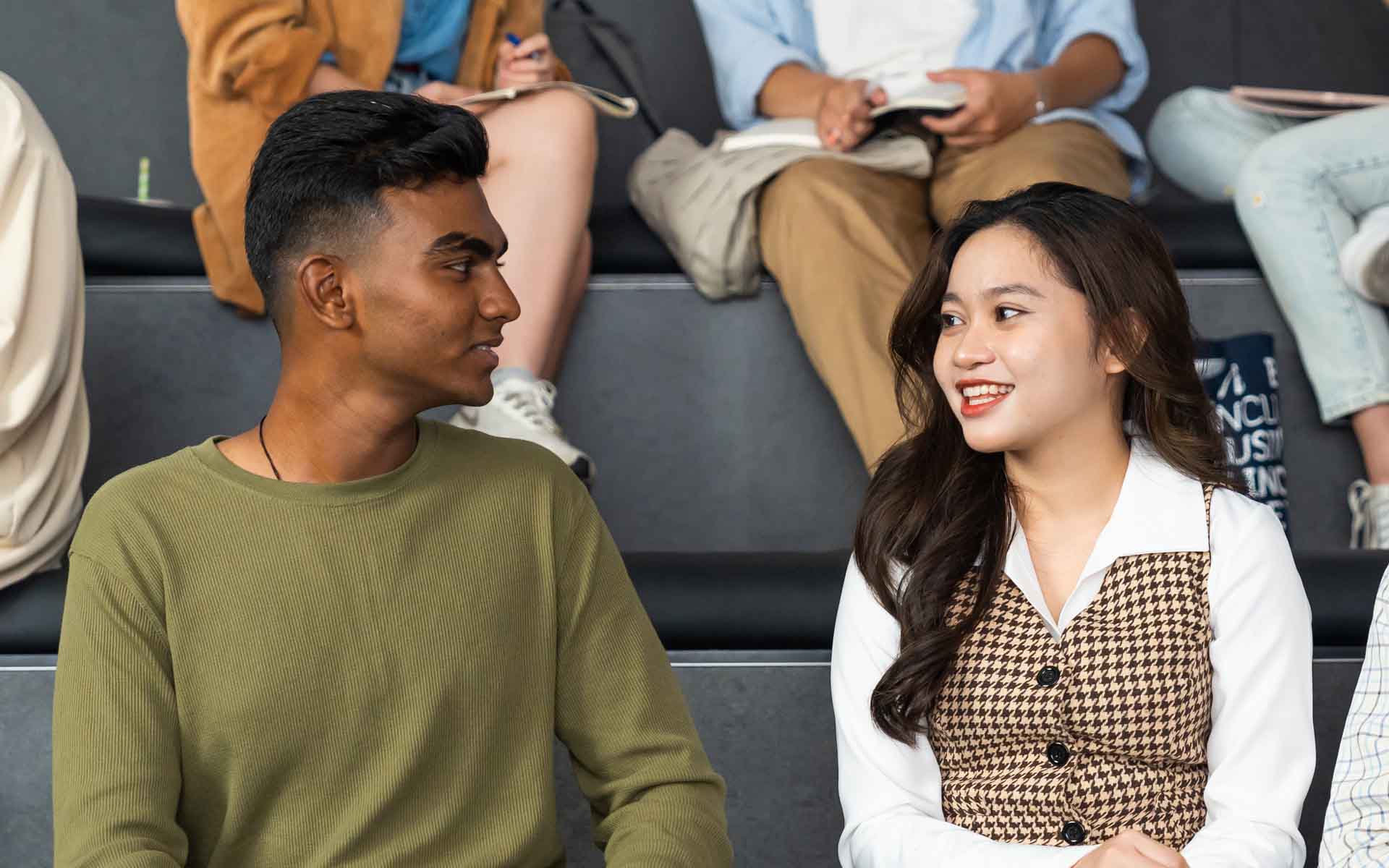 two students one male and one female sitting together in a lecture hall for an educational session