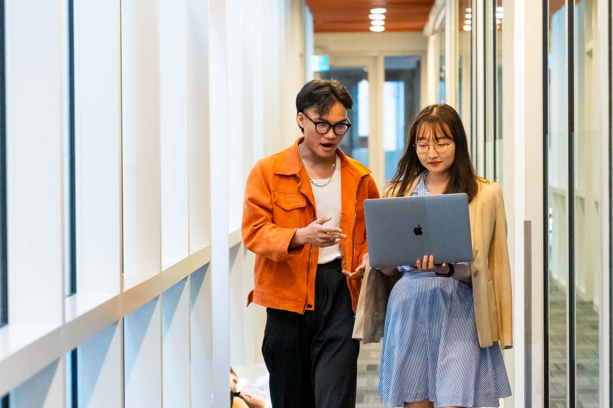 two students one male and one female walking in the office hallway