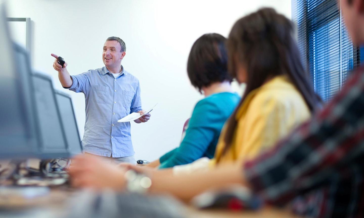 Students at computers looking at the teacher