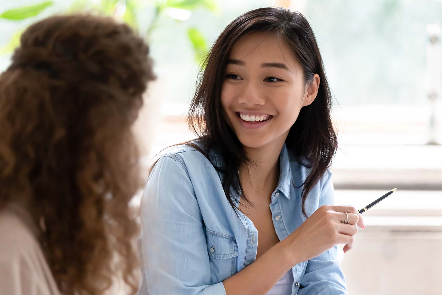 Asian student girl looking at group mate talking studying learn prepare for exam sitting in classroom, diverse friends employees working together on new project communicating discussing concept image