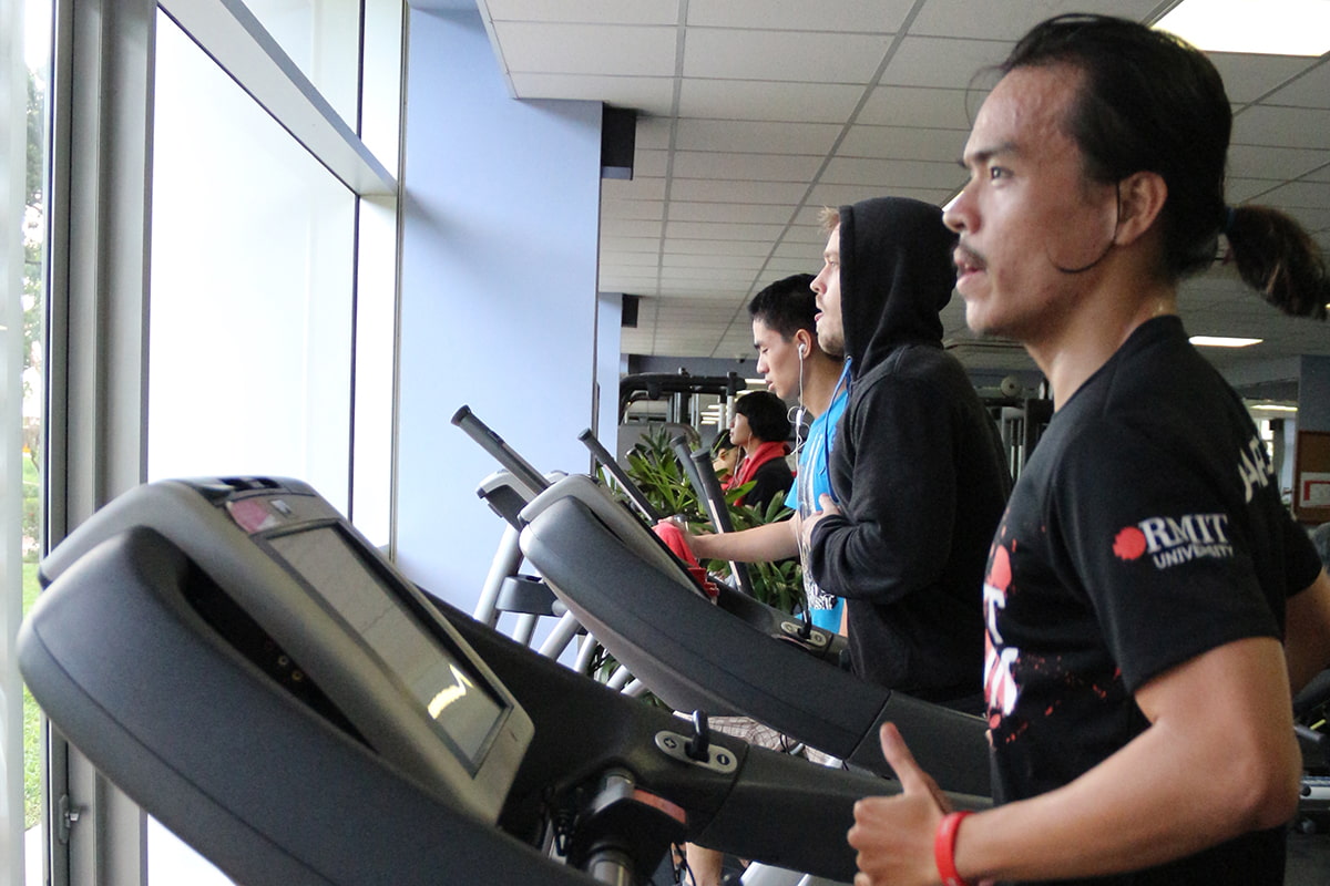 Man excercising on tredmill wearing RMIT shirt.