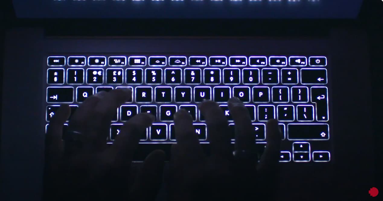 dark image with a backlit keyboard and hands typing